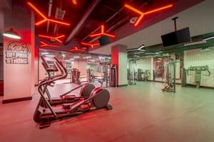 Innenansicht des Fitnesscenters im Delphin Palace Hotel mit roter Beleuchtung und Fitnessgeräten.