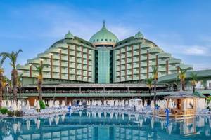 Außenansicht des Delphin Palace Hotels mit großen grünen Kuppeln, Swimmingpool und vielen Liegestühlen.
