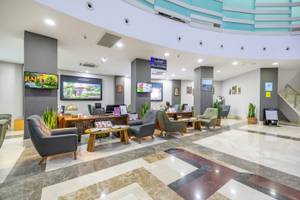 Empfangshalle des VONRESORT Golden Coast mit modernem Design, Sitzbereichen, Tischen, Pflanzen und Monitoren.