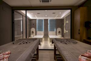 Spa-Behandlungsraum im VONRESORT Golden Coast mit zwei Massagetischen und Glaswänden.