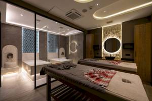 Spa-Behandlungsraum im VONRESORT Golden Coast mit zwei Massagetischen und Glaswänden.