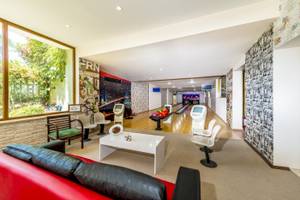 Bowlinghalle im VONRESORT Golden Coast mit Bowlingbahnen, Sitzmöbeln und einem Fenster mit Gartenblick.