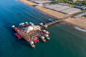 Luftaufnahme des VONRESORT Golden Coast mit mehreren Pavillons und Sonnenschirmen am Meer.