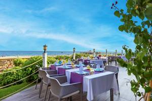 Außenterrasse des VONRESORT Golden Coast mit Tischen und Stühlen, Blick auf den Strand