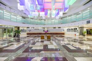 Empfangsbereich des VONRESORT Golden Coast mit farbenfroher Deckenbeleuchtung und Marmorboden.