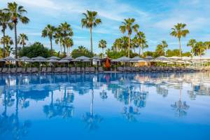 Außenpool des VONRESORT Golden Coast mit vielen Liegen, Sonnenschirmen und Palmen