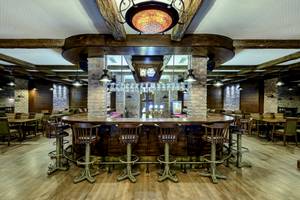 Innenansicht der Bar im VONRESORT Golden Coast mit runden Holztischen und Stühlen.