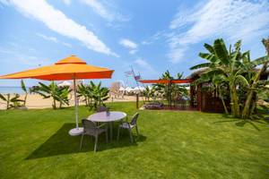 Außenbereich des VONRESORT Golden Coast mit Tisch, Stühlen und Sonnenschirm am Strand