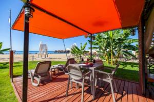 Terrasse des VONRESORT Golden Coast mit Esstisch und Sonnenschirm am Strand