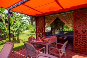 Sitzecke im Freien des VONRESORT Golden Coast mit rotem Sonnendach und grüner Wiese.