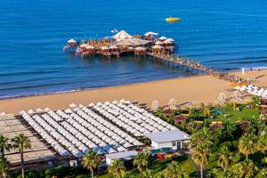 Luftaufnahme des VONRESORT Golden Coast am Strand mit vielen Sonnenschirmen und Palmen