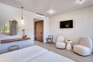 Innendesign eines Zimmers im Georgioupolis Resort Aquapark & SPA mit weißen Möbeln und einer Terrasse.