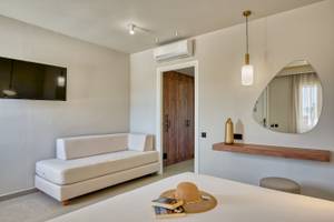 Innenansicht eines Zimmers im Georgioupolis Resort Aquapark & SPA mit Bett, Sofa und Fernseher.
