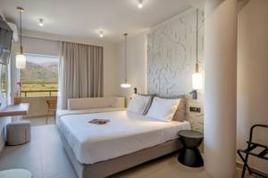 Ein modernes Hotelzimmer im Georgioupolis Resort Aquapark & SPA mit einem großen Bett und einem Sofa.