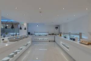 Innenansicht des Restaurants im Georgioupolis Resort Aquapark & SPA Hotel mit weißen Tischen und Buffets.