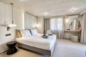 Hotelzimmer im Georgioupolis Resort Aquapark & SPA mit weißem Bett, Möbeln und Dekor.