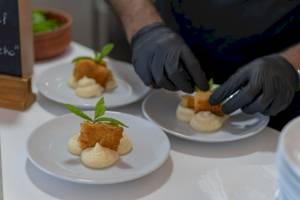 Eine Person bereitet Gerichte auf weißen Tellern im Georgioupolis Resort Aquapark & SPA vor.