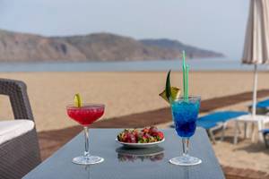 Zwei Cocktails mit Strohhalmen und Obstteller auf einem Tisch am Strand im Georgioupolis Resort.