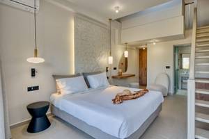 Schlafzimmer im Georgioupolis Resort Aquapark & SPA mit einem Bett, weißen Decken und einem Hut.