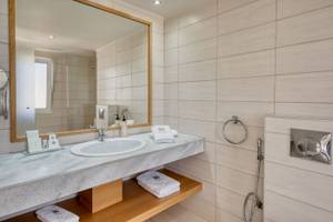 Badezimmer im Georgioupolis Resort Aquapark & SPA mit Marmorwaschbecken und Spiegel.