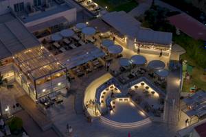 Abendluftaufnahme des Georgioupolis Resort Aquapark & SPA mit beleuchteten Terrassen und Gästen.