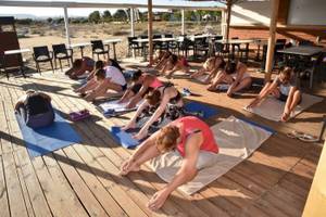 Mehrere Frauen und Männer machen Yoga auf einer Terrasse im Freien im Georgioupolis Resort Aquapark & SPA.
