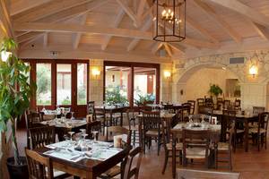 Innenansicht des Restaurants im Cactus Village Hotel mit Holztischen, Stühlen und einem hängenden Kronleuchter.