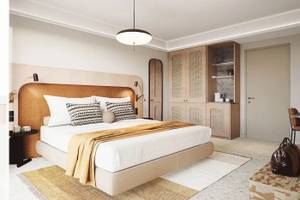 Innenansicht eines Schlafzimmers im Cactus Village Hotel mit einem großen Bett, Dekor und Möbeln.