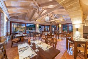 Innenbereich des Restaurants im Cactus Village Hotel & Bungalows mit Holztischen und Stühlen.