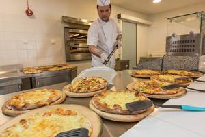 Ein Koch bereitet mehrere Pizzen im Hotel Sun Palace zu.
