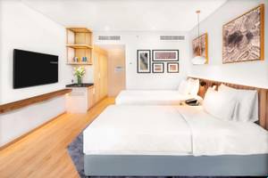 Innenansicht eines Zimmers im Radisson Blu Hotel mit zwei Betten, Fernseher und Kunstwerken an der Wand.