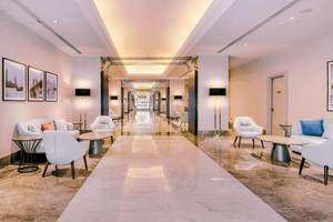 Lobby des Radisson Blu Hotel & Resort, Abu Dhabi Corniche mit weißen Möbeln und langen Flur