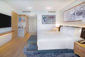 Innenansicht eines Gästezimmers im Radisson Blu Hotel & Resort, Abu Dhabi Corniche, mit Bett, Fernseher, und Dekor.