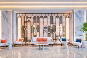 Das elegante Foyer des Radisson Blu Hotel & Resort in Abu Dhabi mit Marmorwänden und geometrischen Glaswänden.