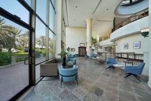 Lobby des Radisson Blu Hotels & Resort in Abu Dhabi mit blauen Stühlen und Tischen.