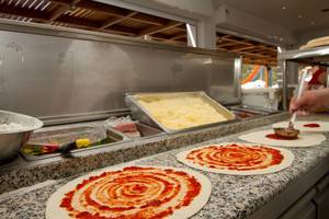 Pizzas werden im Sun Palace Hotel zubereitet, mit Tomatensoße und Käse darauf.