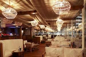 Innenansicht des Restaurants im Radisson Blu Hotel mit weißen Sofas und Rattan-Stuhl in Abu Dhabi Corniche.