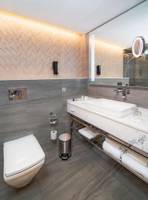 Badezimmer im Radisson Blu Hotel & Resort, Abu Dhabi Corniche mit grauen Wänden, Marmor-Waschtisch und Toilette.