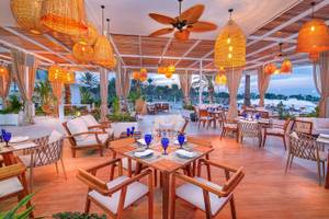 Innenbereich des Restaurants im Radisson Blu Hotel & Resort, Abu Dhabi Corniche, mit hängenden Lampen und gedeckten Tischen.