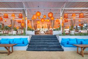 Terrasse des Radisson Blu Hotel & Resort in Abu Dhabi Corniche mit orangefarbenen Lampen und blauen Kissen