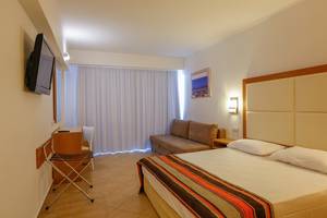 Hotelzimmer im Sun Palace mit Bett, Sofa, Fernseher und Schreibtisch.