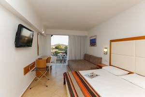 Hotelzimmer im Sun Palace mit Fernseher, Bett, Couch, Schreibtisch und Balkonzugang.