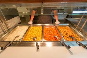 Buffettisch mit Reis, Curry und Gemüse, ein Mitarbeiter im Hintergrund.