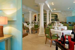 Restaurant Ambiente im JOIA Bávaro by Iberostar Hotel mit Tisch, Stühlen und Flaschen.