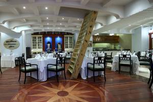 Innenansicht des Restaurants im JOIA Bávaro Hotel mit gedeckten Tischen und einer Leiter.