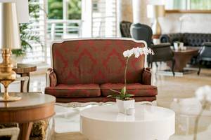 Hotellobby des JOIA Bávaro by Iberostar mit rotem Sofa, weißer Tisch und weißen Orchideen