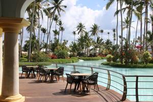 Außenterrasse des JOIA Bávaro by Iberostar mit Tischen und Stühlen und Blick auf einen Wasserweg und Palmen.