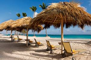 Strand mit Sonnenliegen und Strohschirmen im JOIA Bávaro by Iberostar Hotel