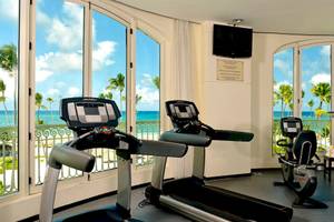 Fitnessraum im JOIA Bávaro by Iberostar Hotel mit Blick auf das Meer und Palmen.
