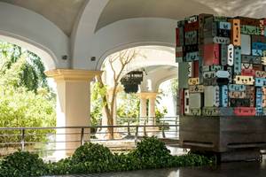 Eingangsbereich des Hotels JOIA Bávaro by Iberostar mit einer großen, bunten Koffer-Skulptur.